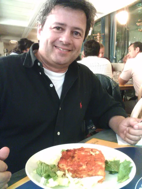 Marco Lungo sorridente a tavola, davanti a un piatto di lasagna